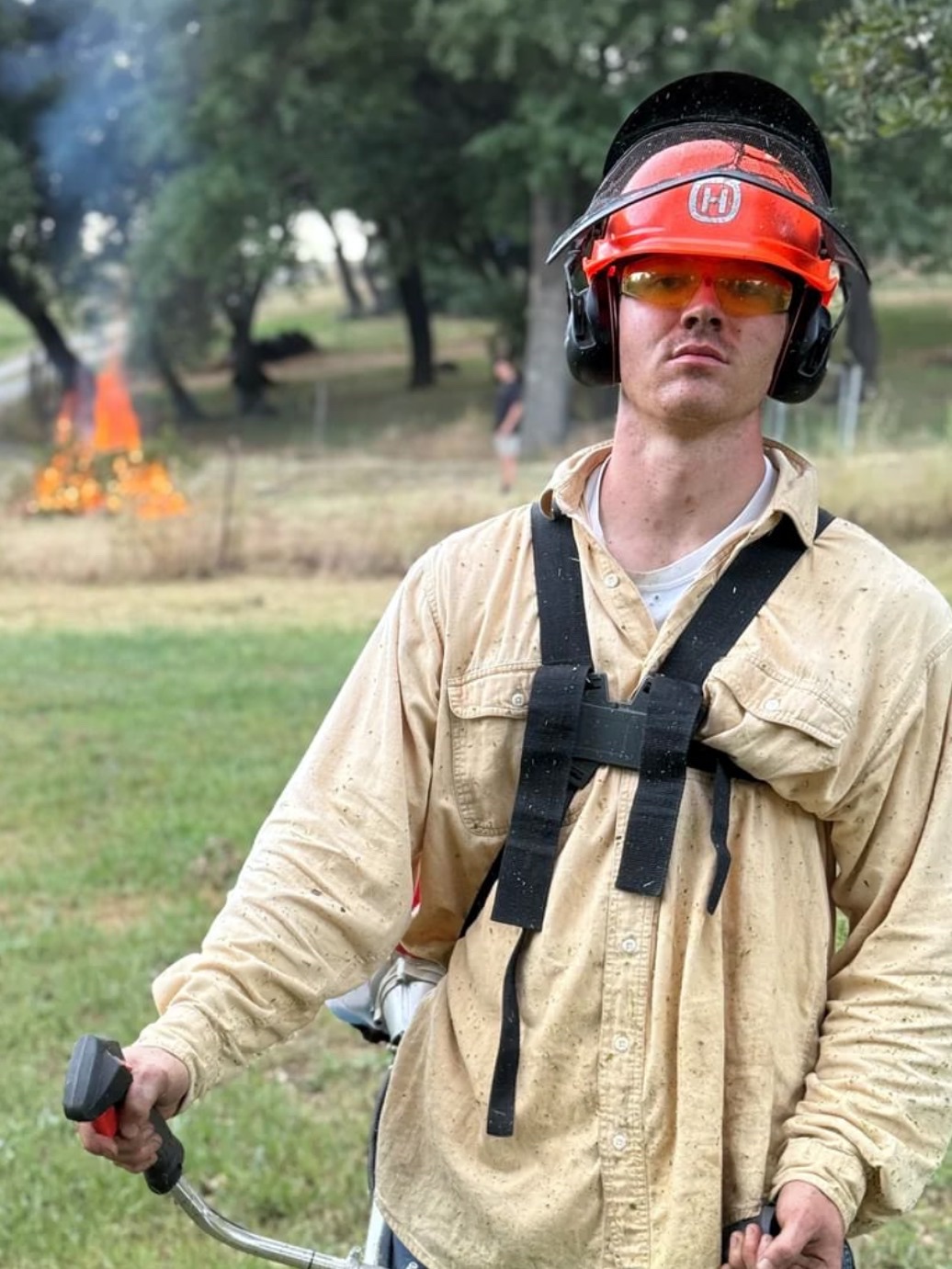 Vazul Hites in a helmet and safety glasses, holding a trimmer on a brush clearing job